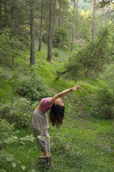 A woman practices yoga in a serene forest, embodying harmony with nature.