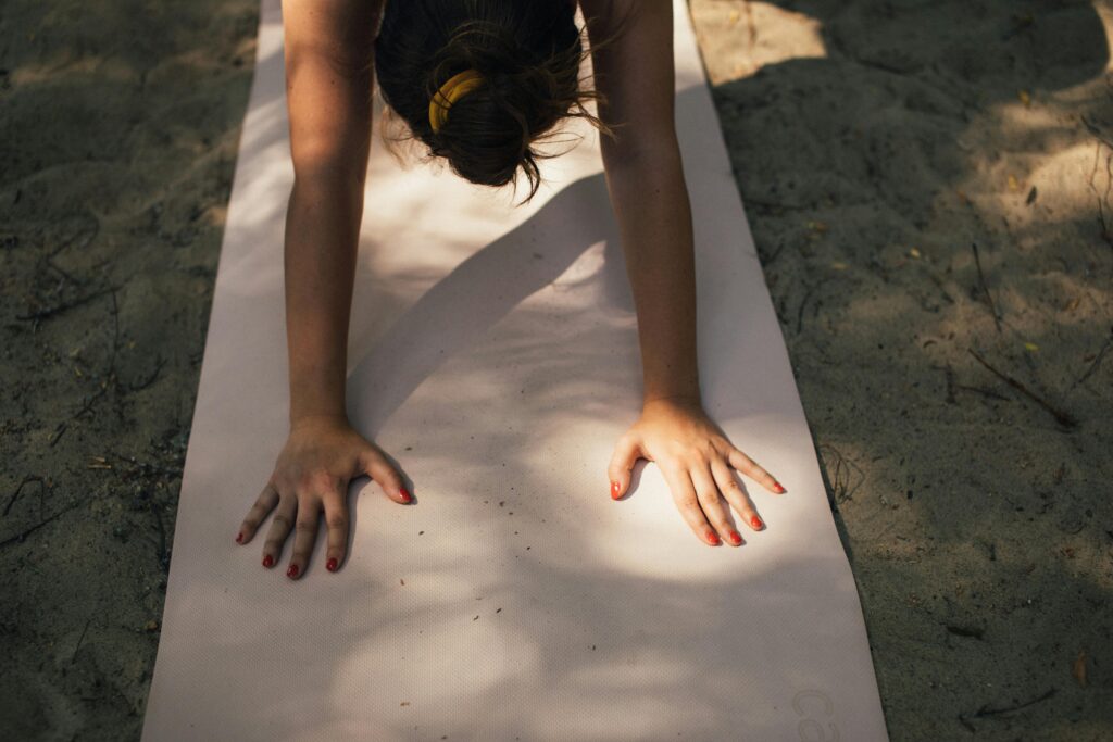 A woman exercises on a yoga mat in outdoor sunlight, promoting fitness and relaxation.