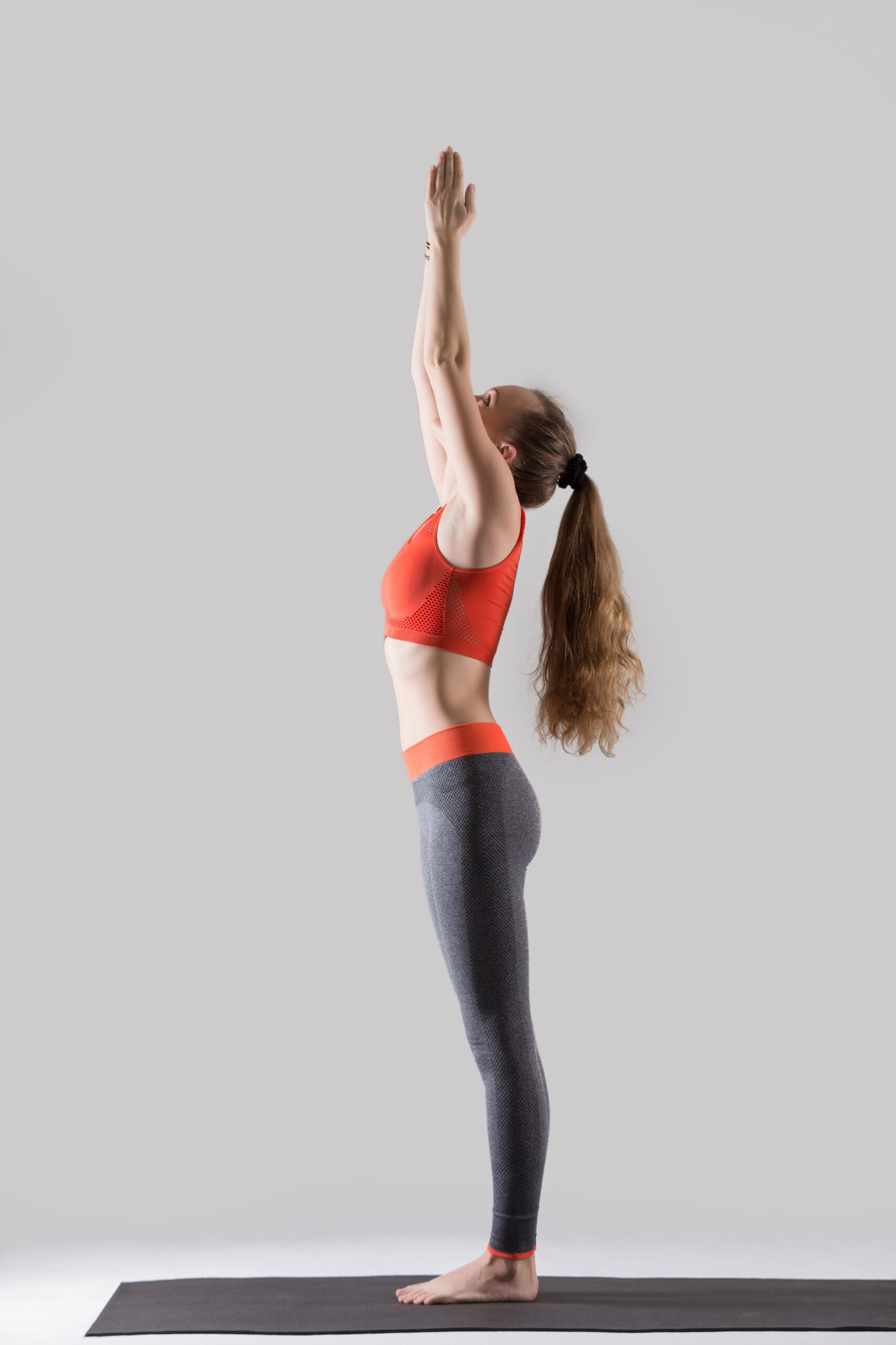 young attractive woman standing in tadasana pose, grey studio ba